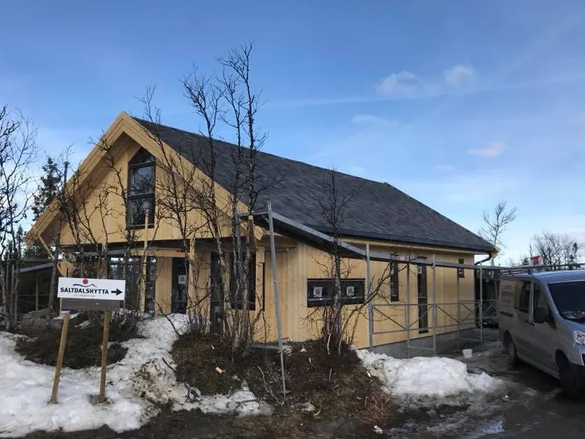 Ferdig hytte med mørkt tak i bjørkeskogen