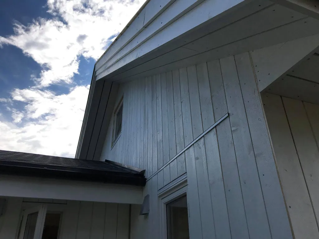 Hvitt hus med glassgavl, stående kledning og hjørner