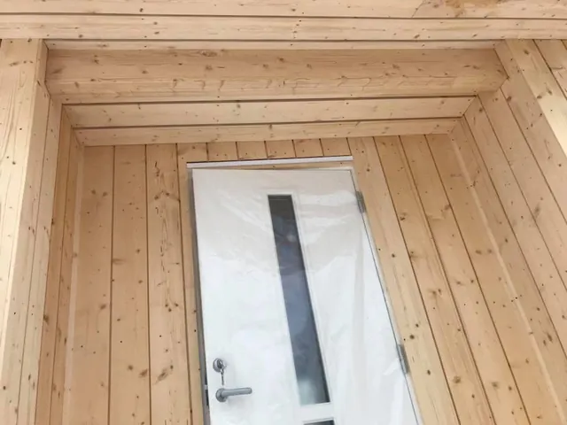 Hvit inngangsdør med smal glassrute, i et rom med panel