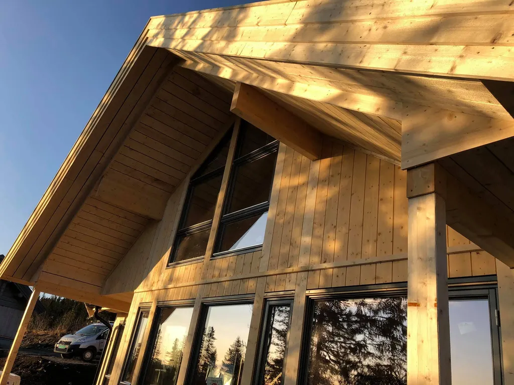 Hytte i kveldssol, gavlen med store vinduer og himling i tre