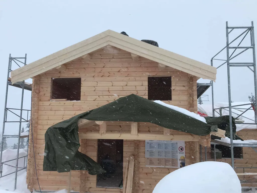 Laftehus i to etasjer, presenning over inngangen om vinteren