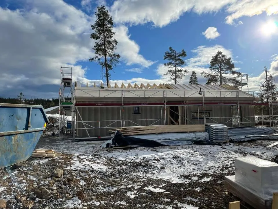 Lang hytte i snø, takstoler og stillas